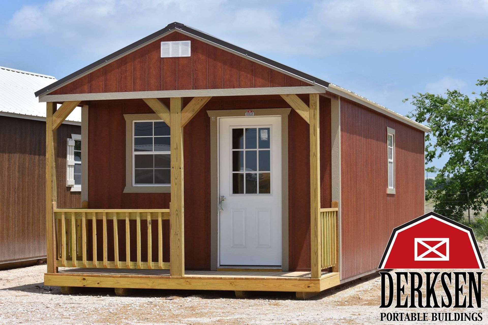 A red shed with a porch and a sign that says derksen portable buildings