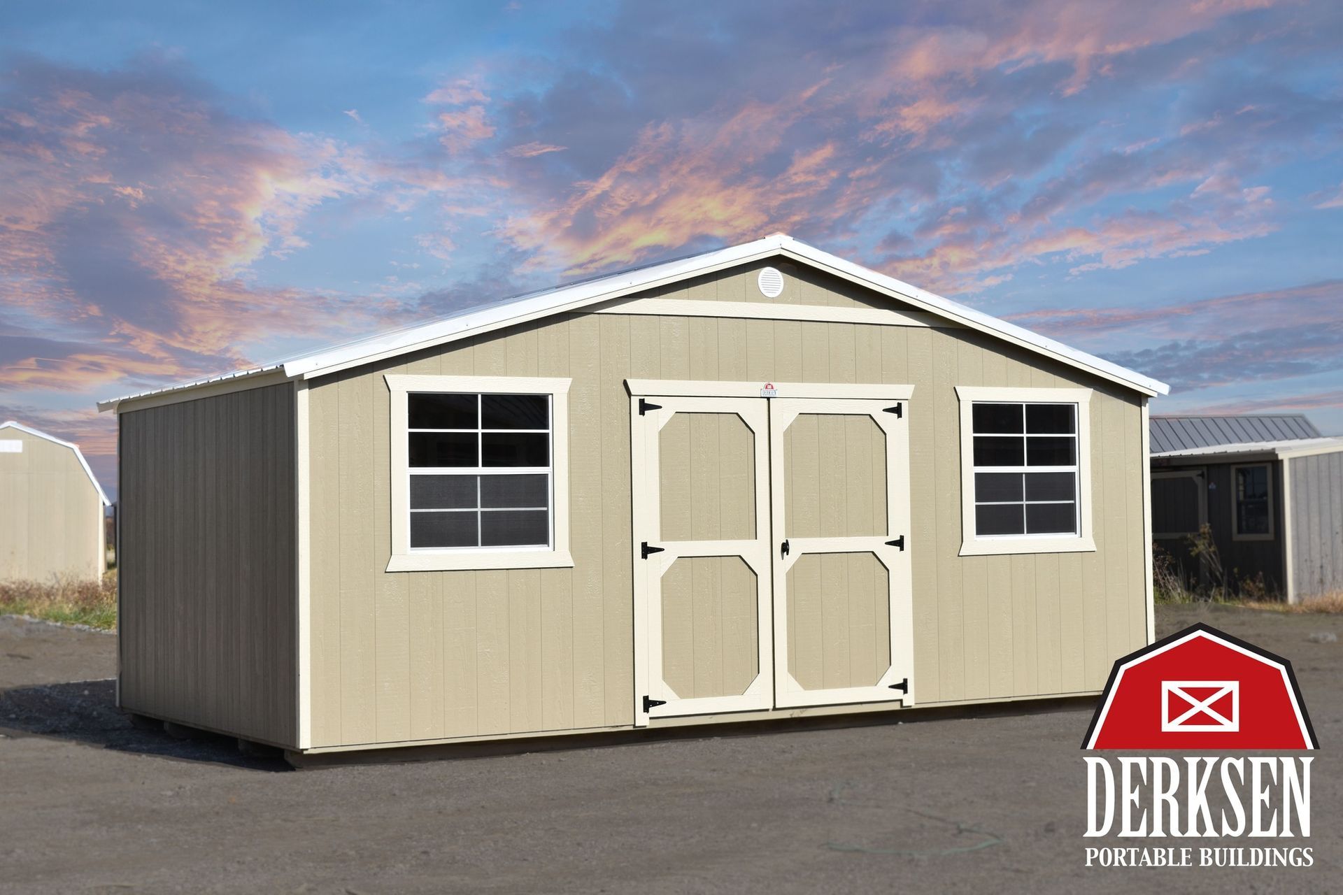 A beige shed with white trim is sitting in a parking lot.