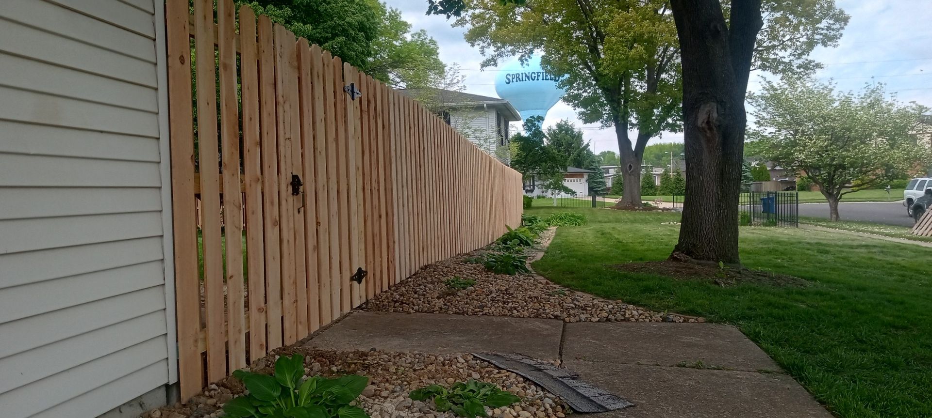 A wooden fence along a sidewalk next to a house.