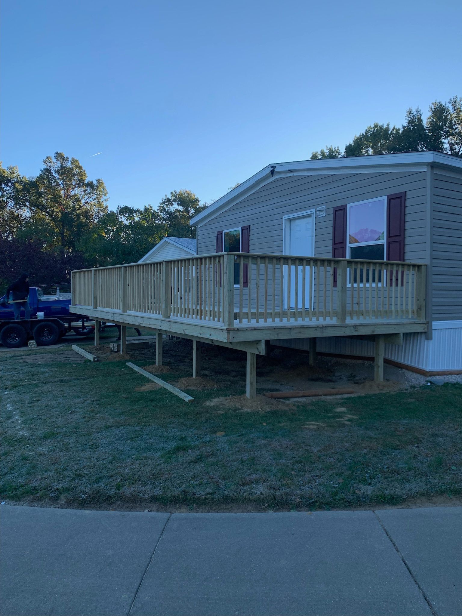 A mobile home with a wooden deck and stairs.