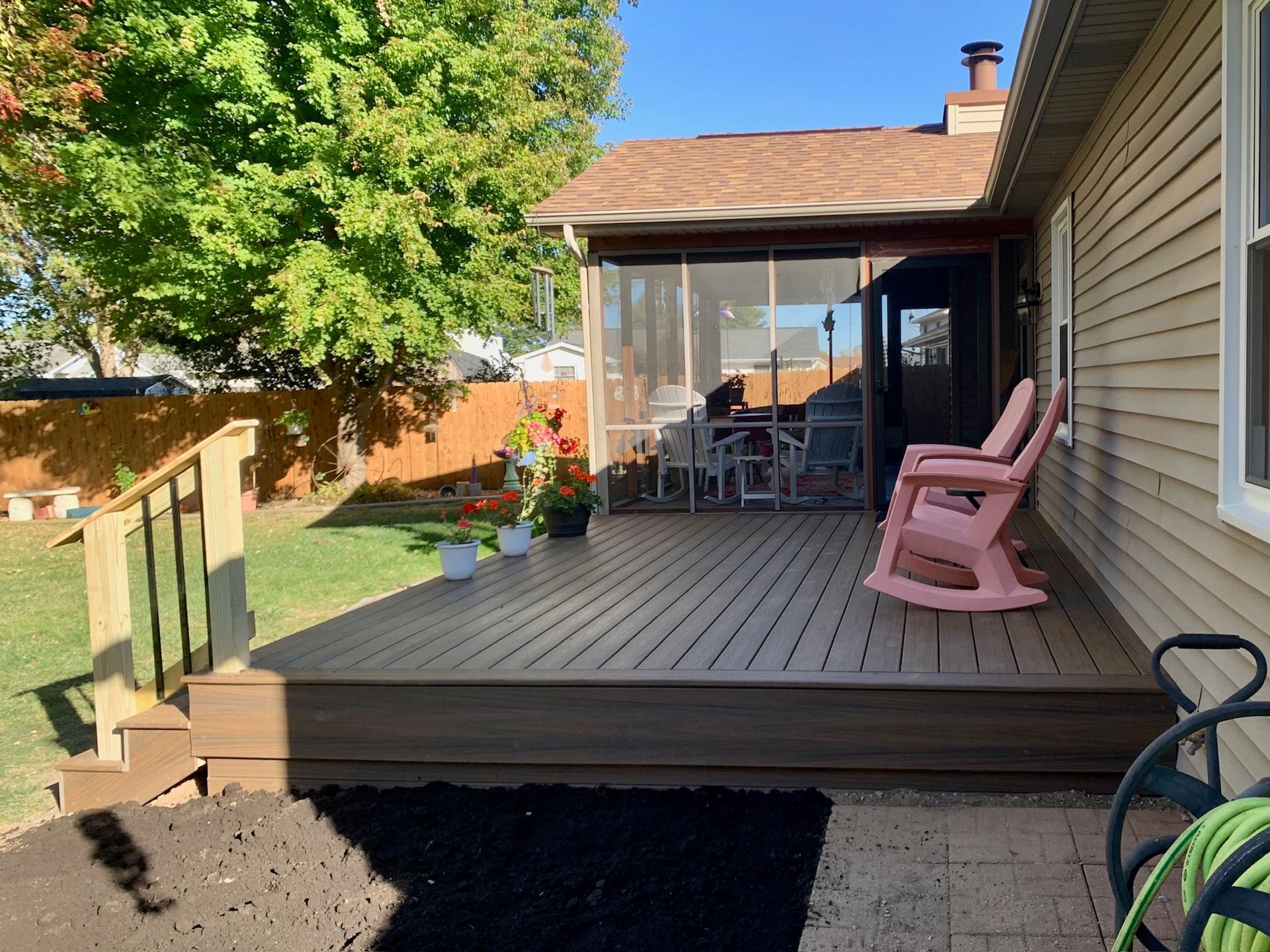 A wooden deck with two rocking chairs on it in front of a house.