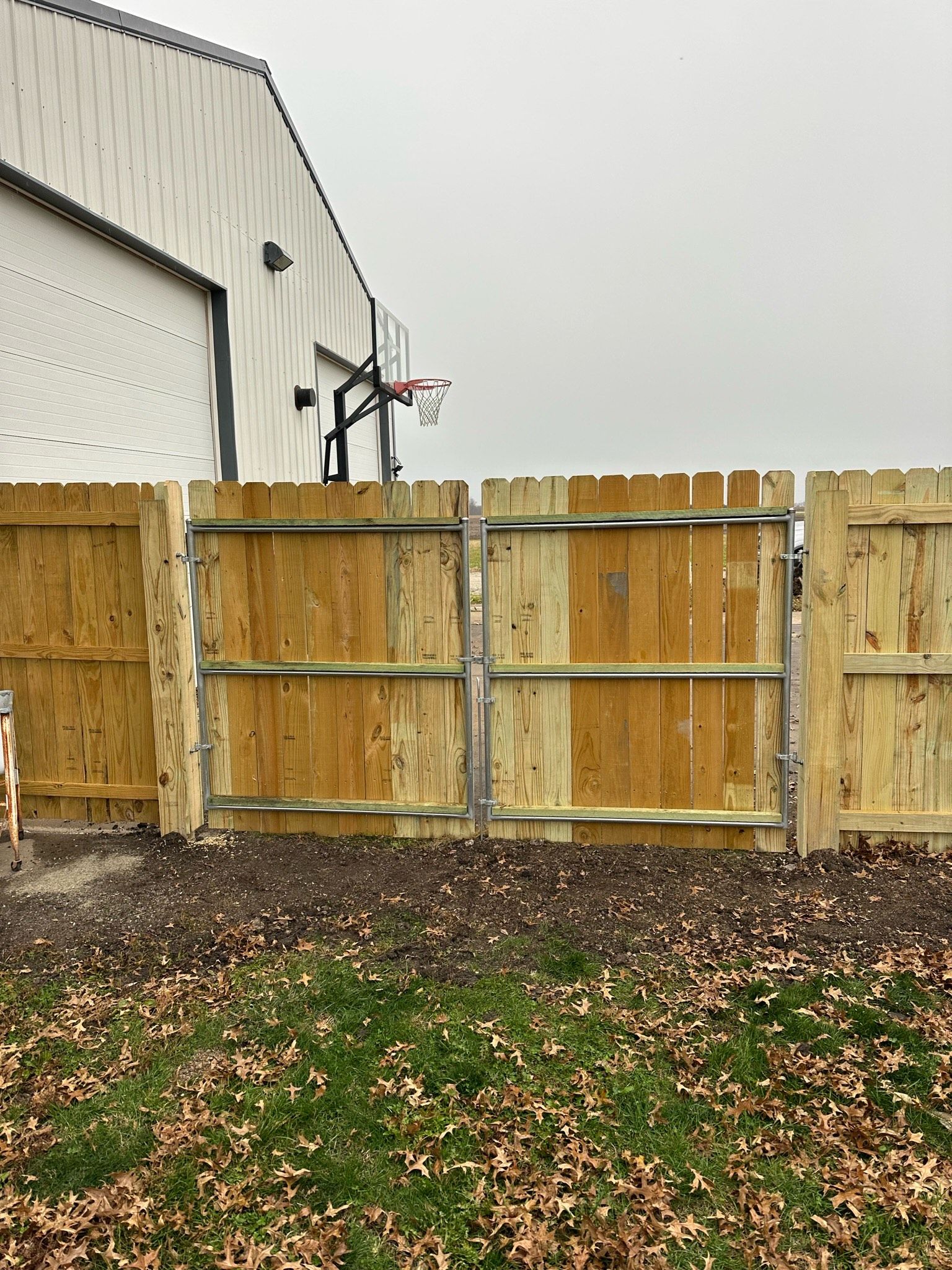 A wooden fence with a basketball hoop in the background.
