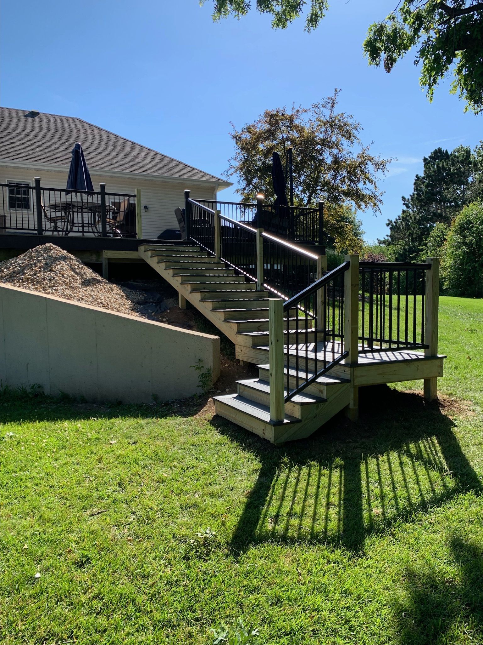 A wooden deck with stairs leading up to it and a house in the background.