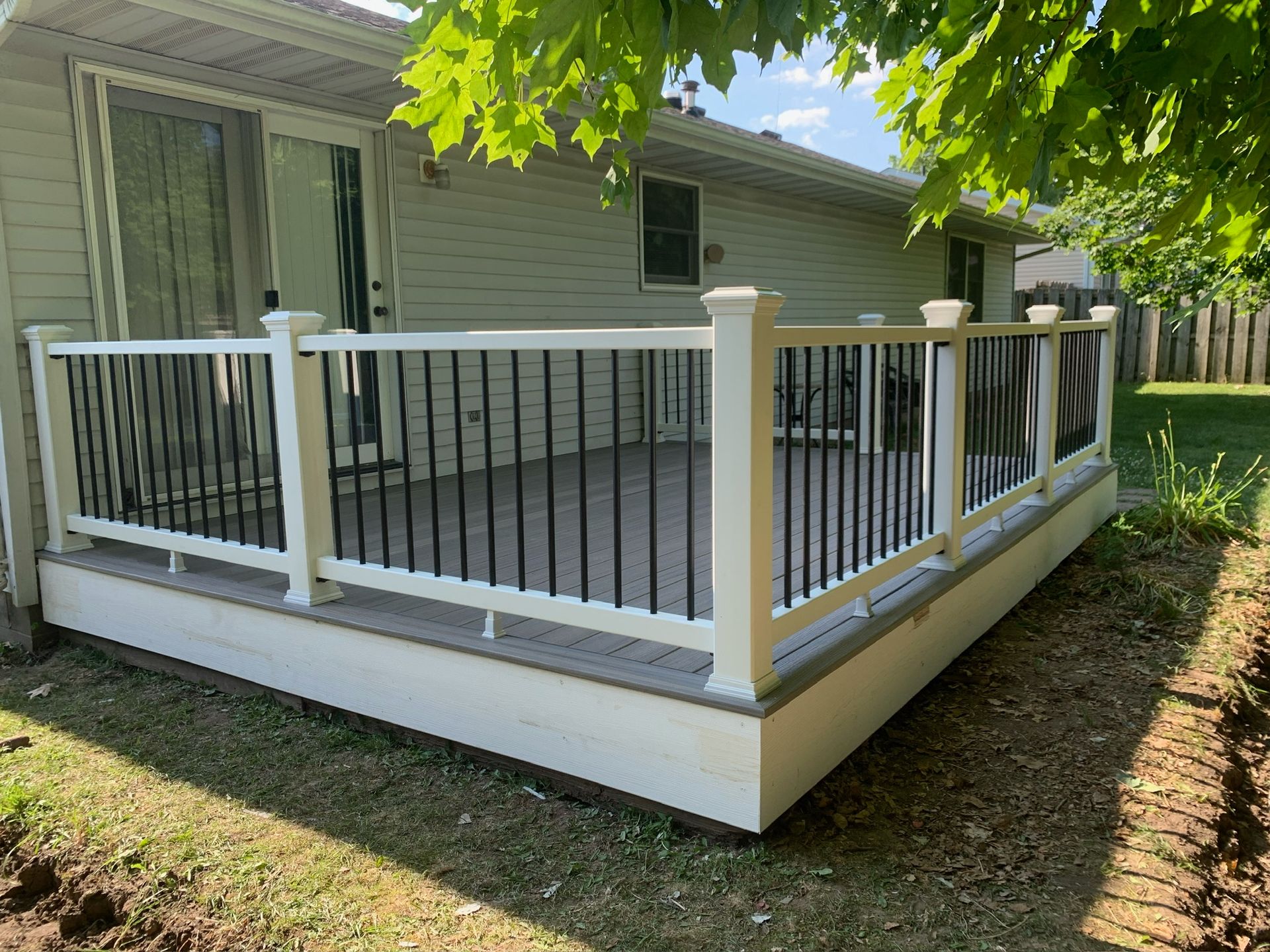 A white deck with a black railing is in front of a house.