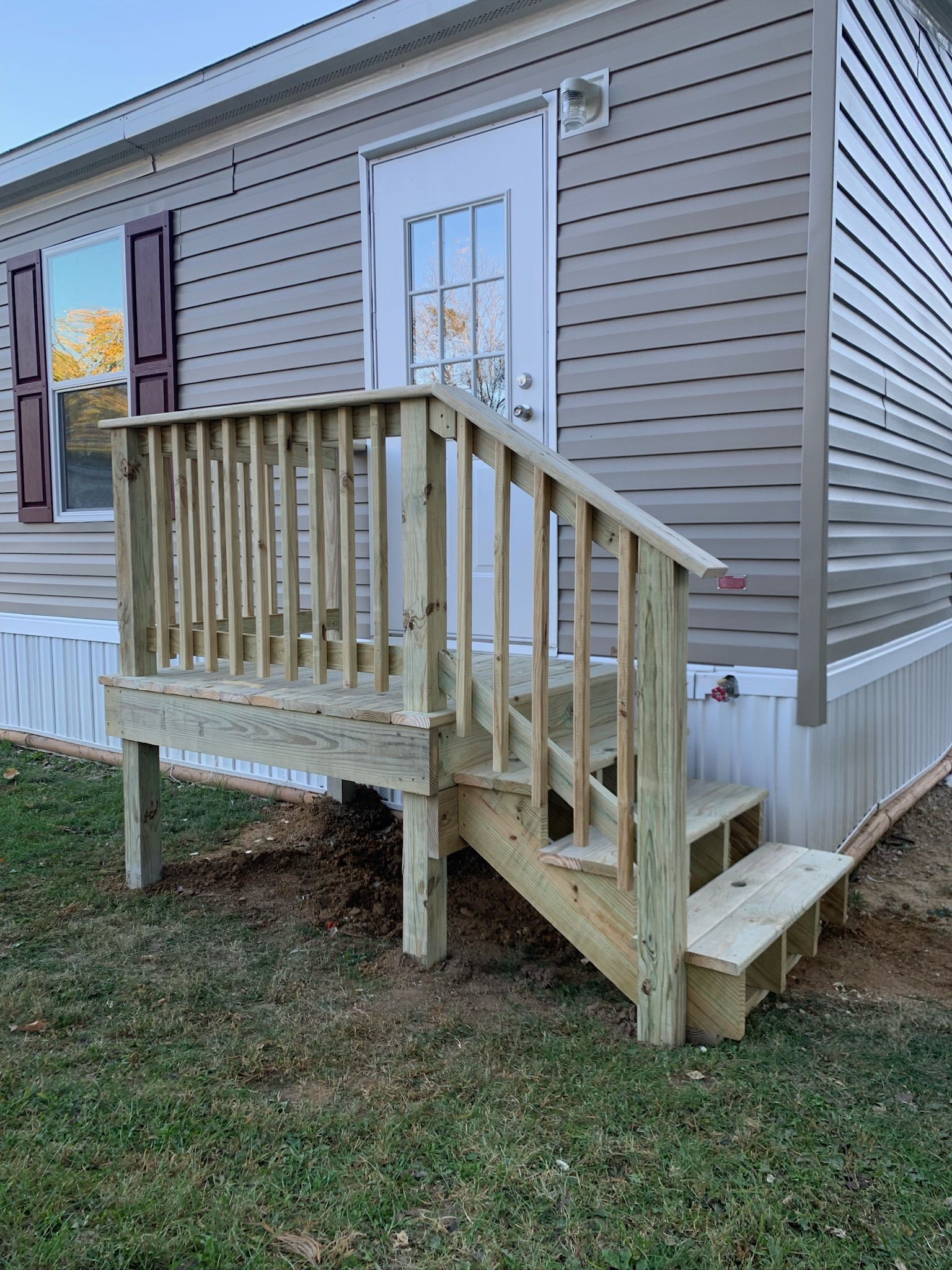 A mobile home with a wooden deck and stairs.
