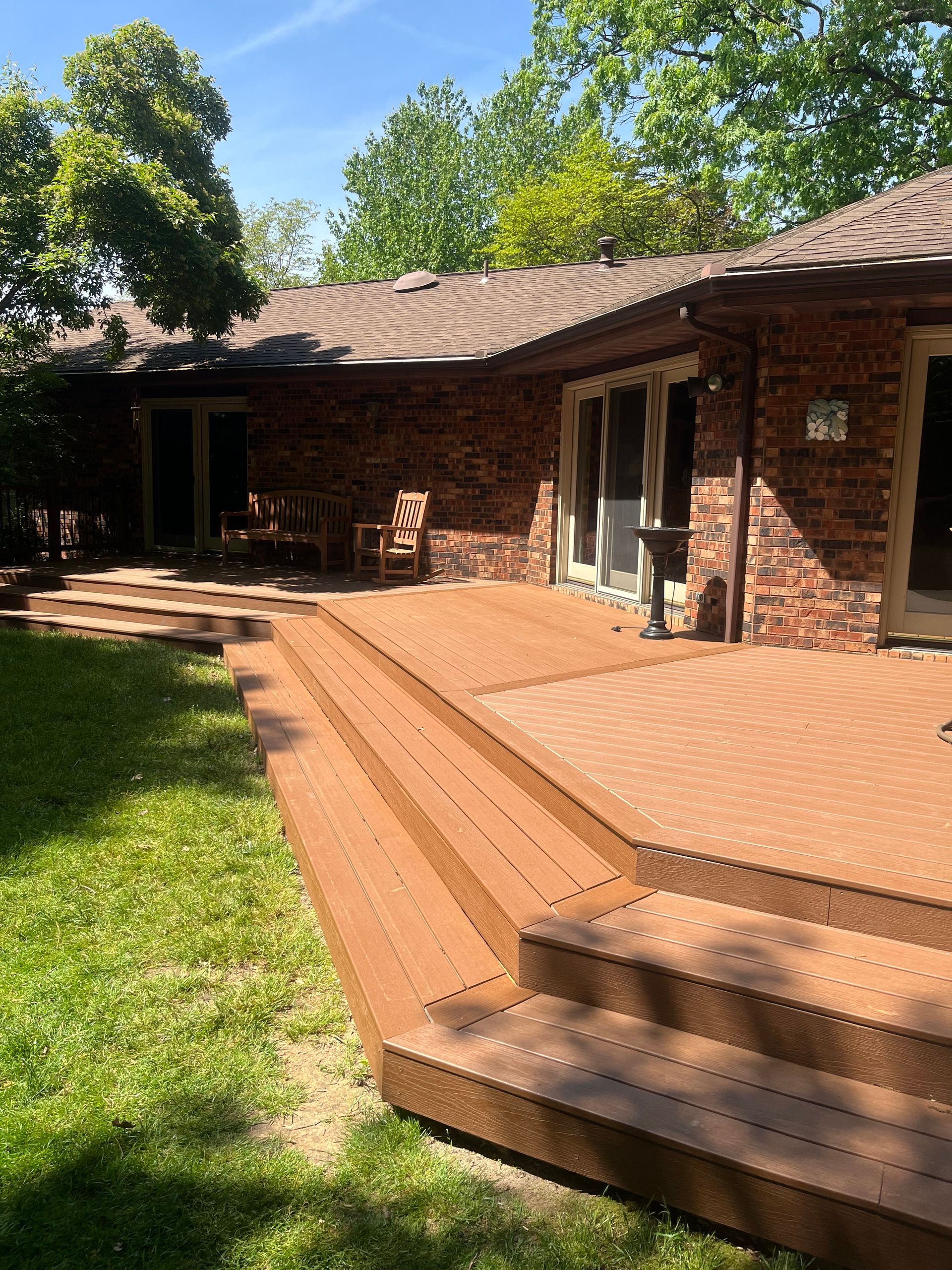 A brick house with a wooden deck and stairs in front of it.