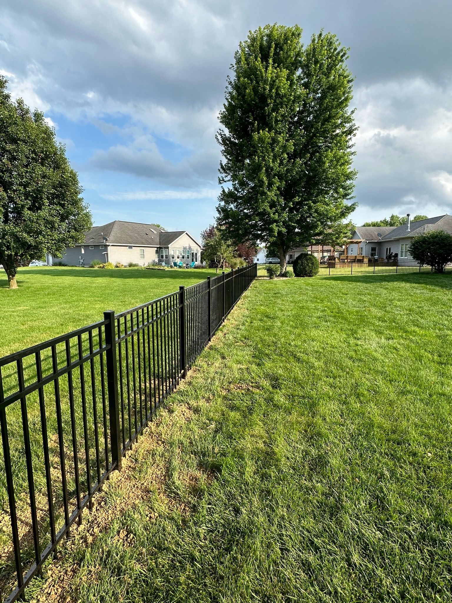 A wooden fence with a gate and a brick building in the background.