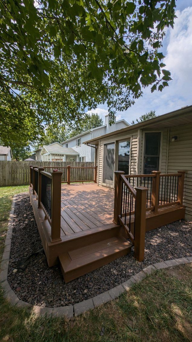 A wooden deck with a pergola and a house in the background