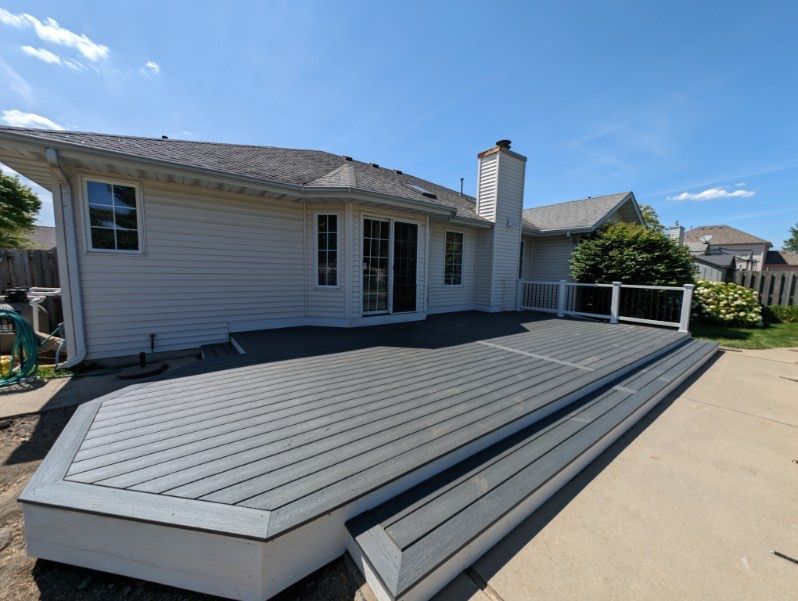 A white house with a gray deck in front of it.