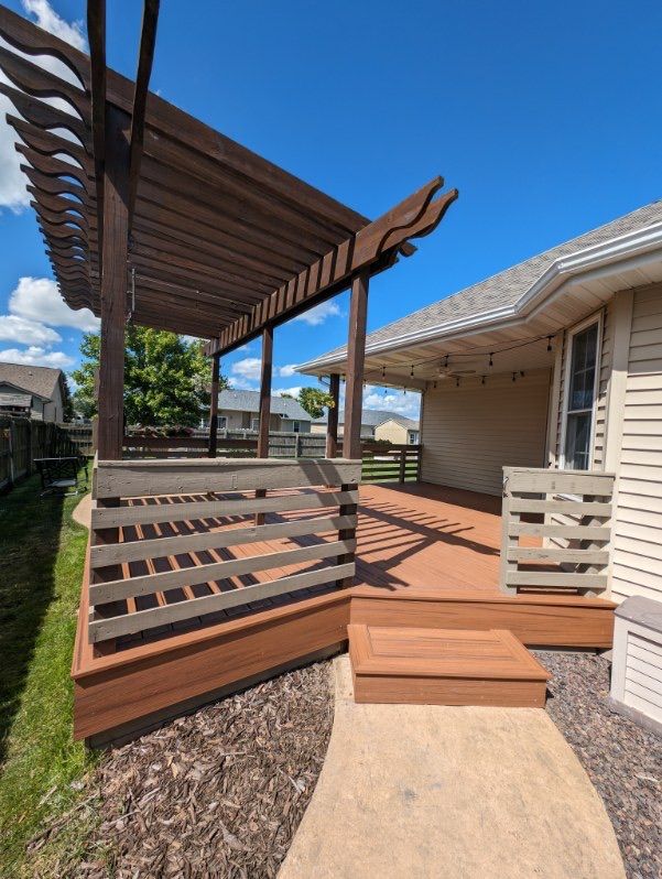A deck with a pergola and stairs leading to it