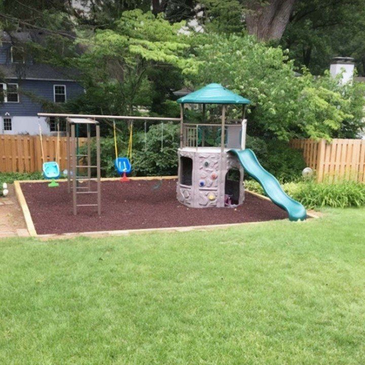 A playground with a slide and swings in a backyard.