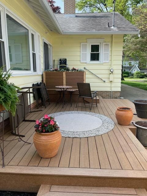 A wooden deck with potted plants and a table and chairs.