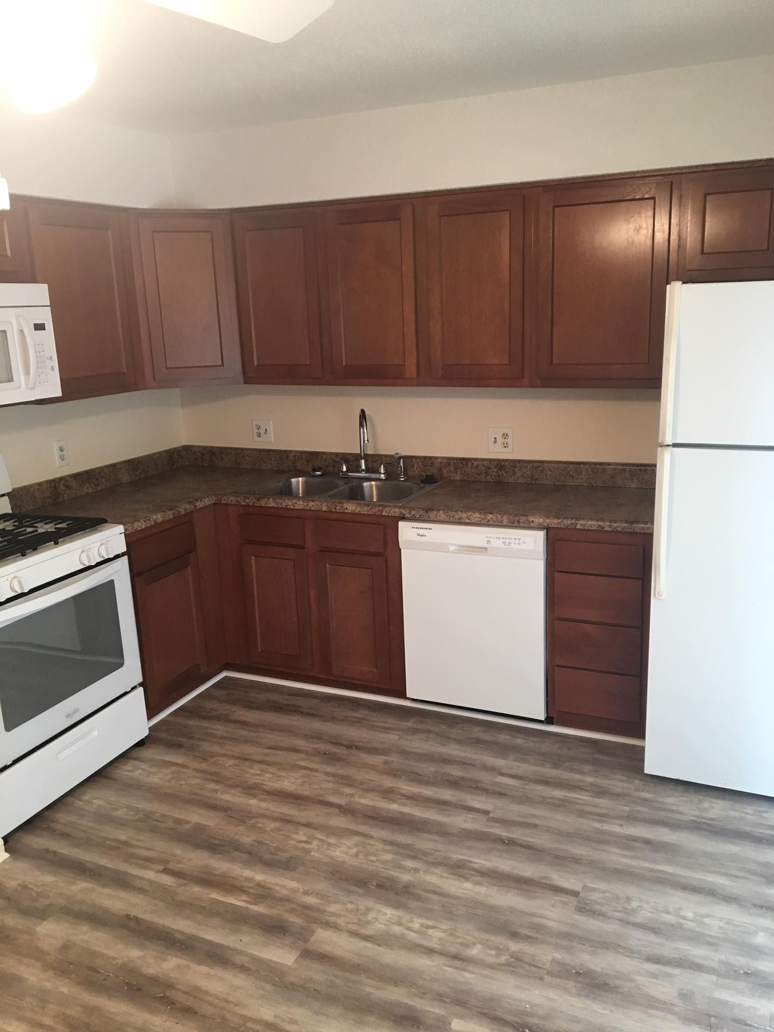 A kitchen with wooden cabinets, a refrigerator, stove, dishwasher, and microwave.