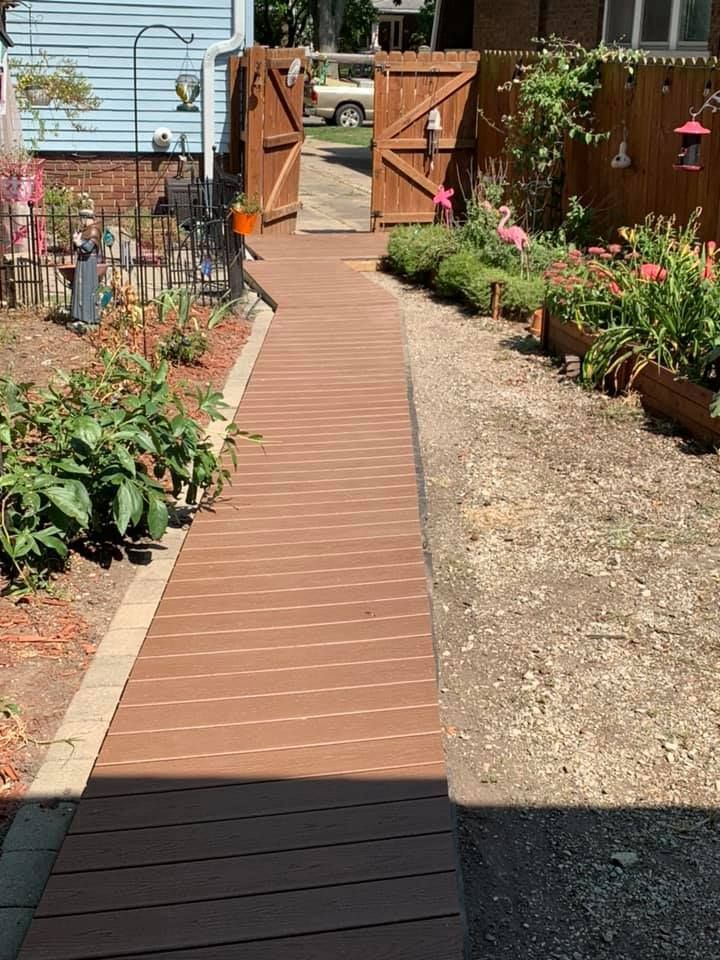 A brick walkway leading to a wooden gate in a garden.