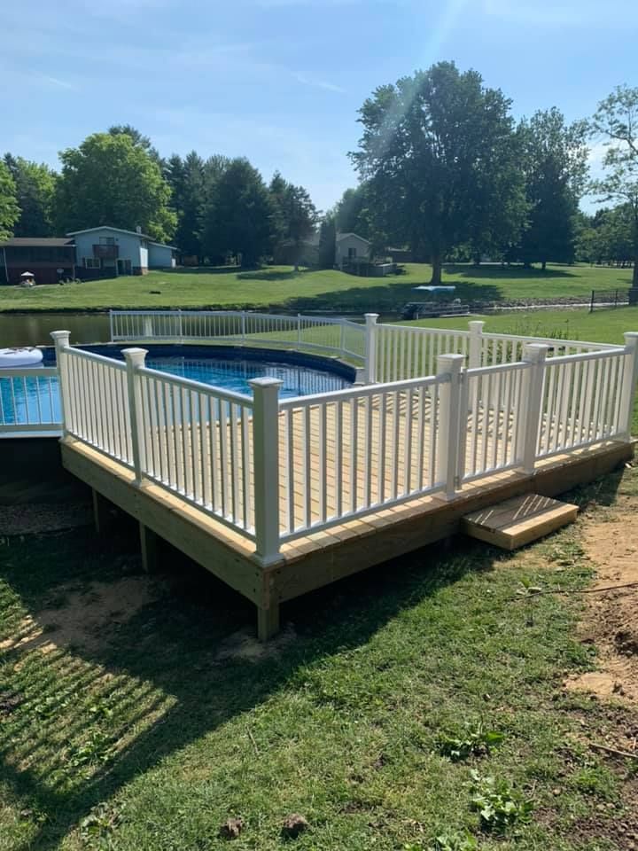A wooden deck next to a swimming pool with a white railing.