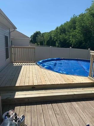 A wooden deck with a swimming pool in the background.