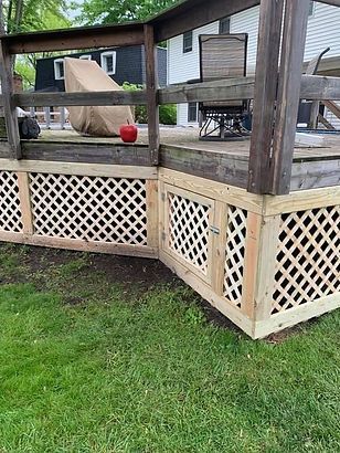 A wooden deck with a lattice fence and a table and chairs on it.