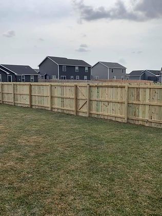 A wooden fence is in the middle of a lush green field.