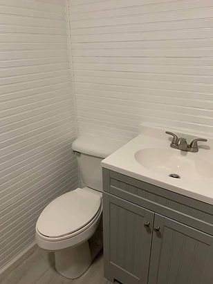 A bathroom with a toilet, sink and vanity.