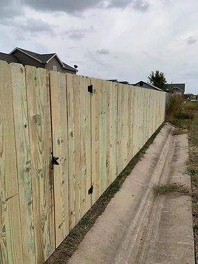 A wooden fence is sitting next to a dirt road.