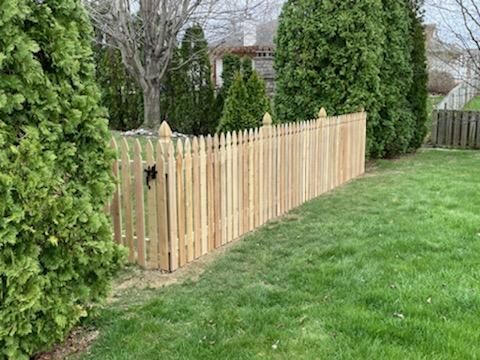 A wooden picket fence surrounds a lush green yard.