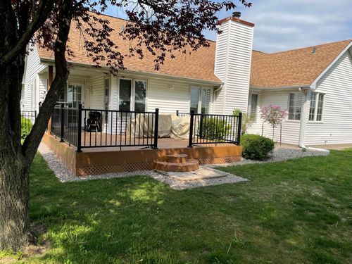 A white house with a deck and stairs in front of it.