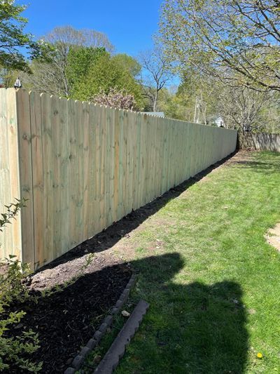 A wooden fence is sitting in the middle of a lush green yard.