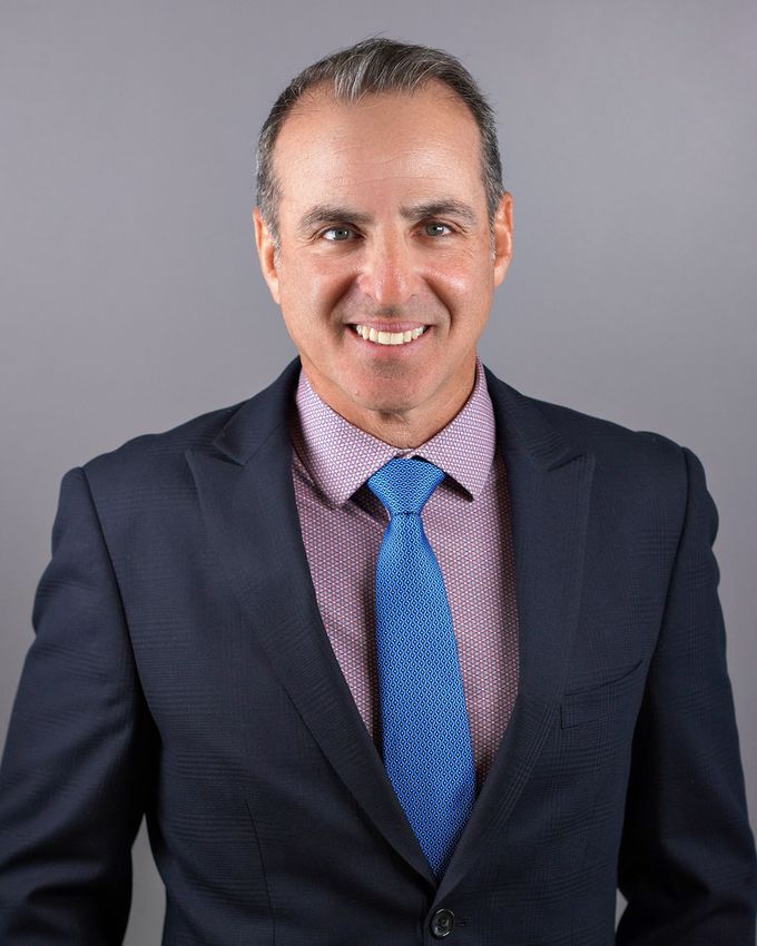 A man in a suit and tie is smiling for the camera