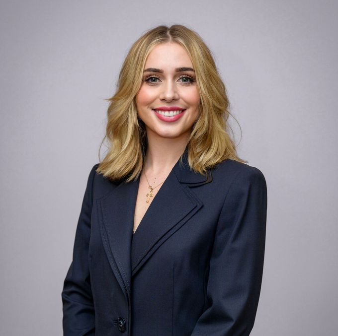 A woman in a blue suit is smiling for the camera