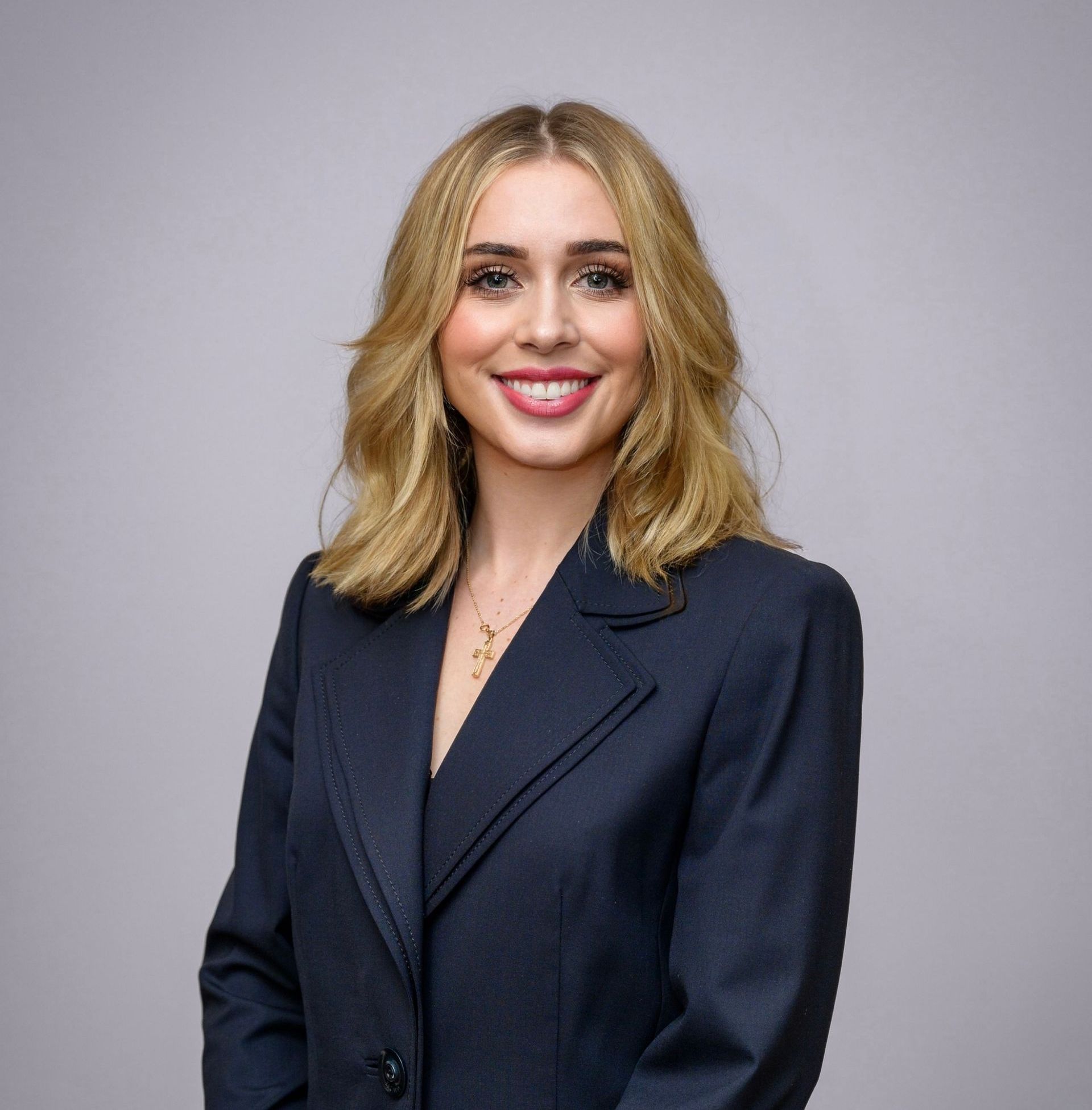 A woman in a suit is smiling for the camera