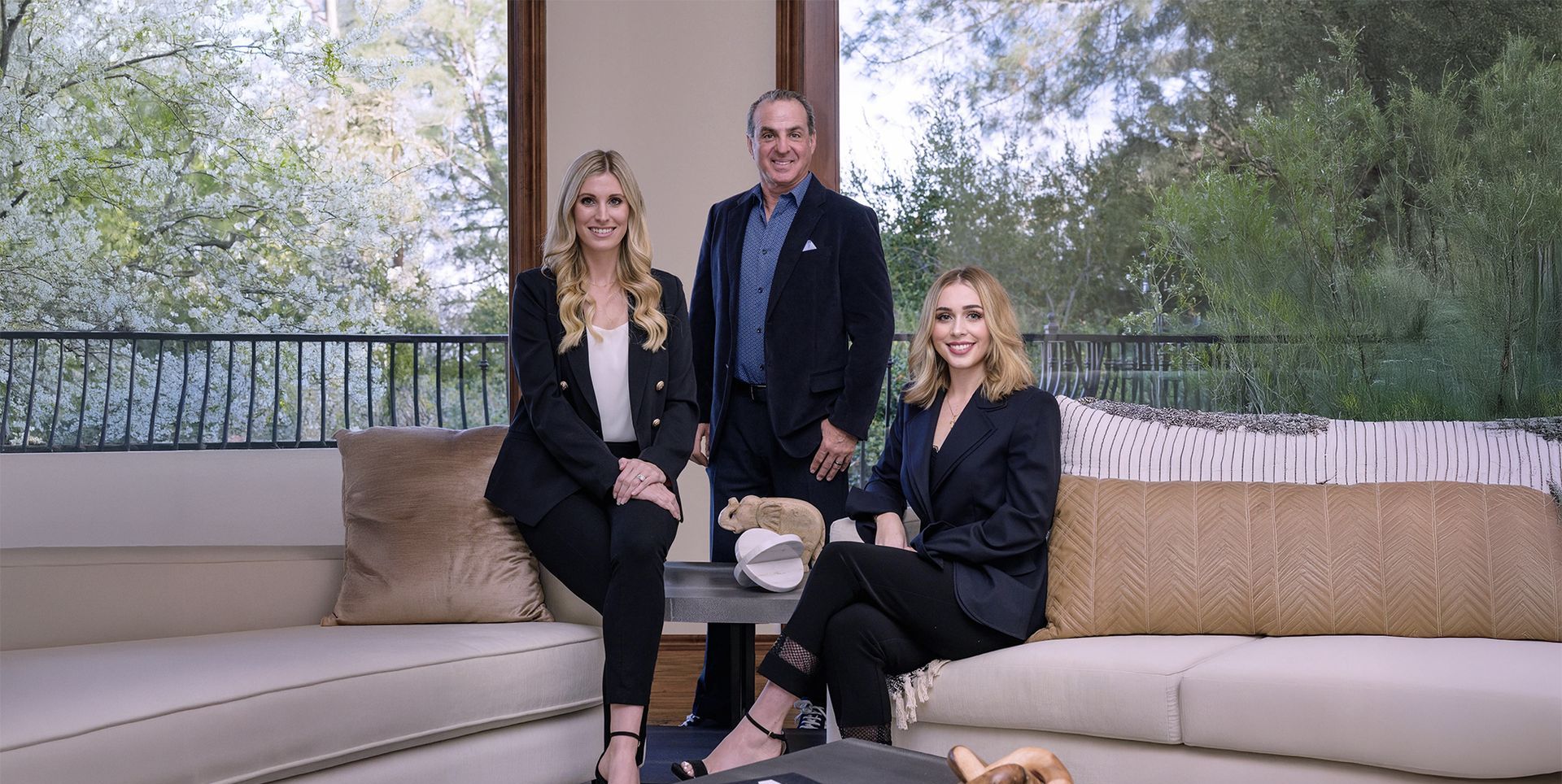 A man and two women are sitting on a couch in a living room.