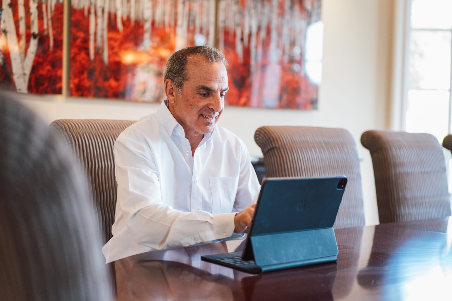 A man is sitting at a table using a tablet computer.