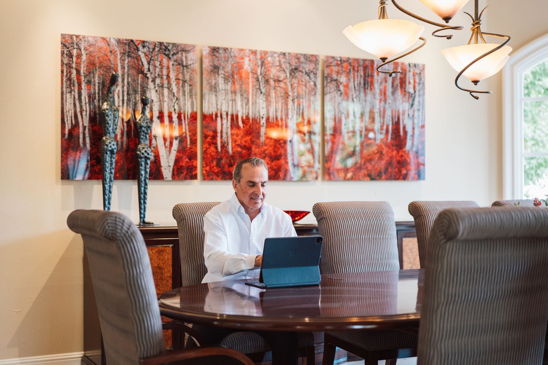 A man is sitting at a table using a laptop computer.