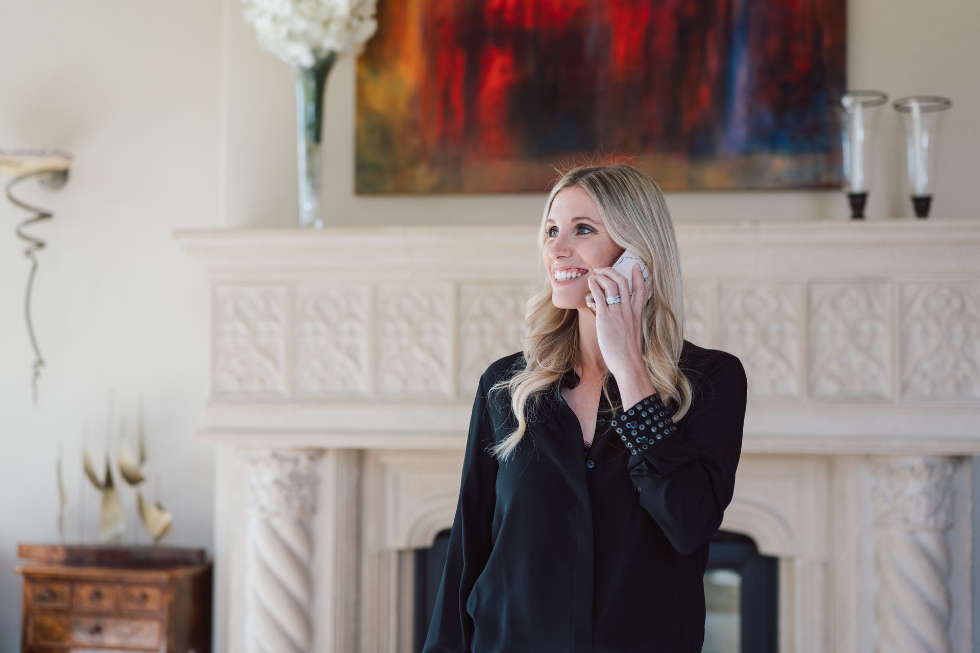 A woman is standing in a living room talking on a cell phone.