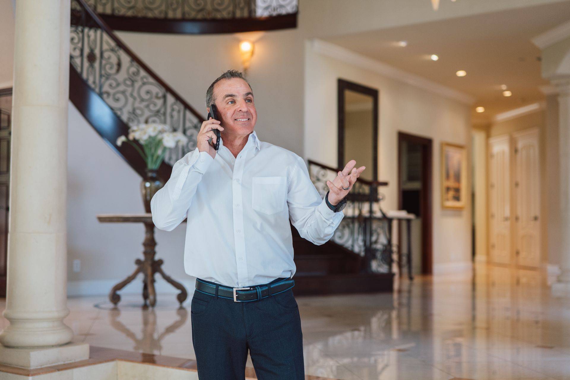 A man is standing in a living room talking on a cell phone.
