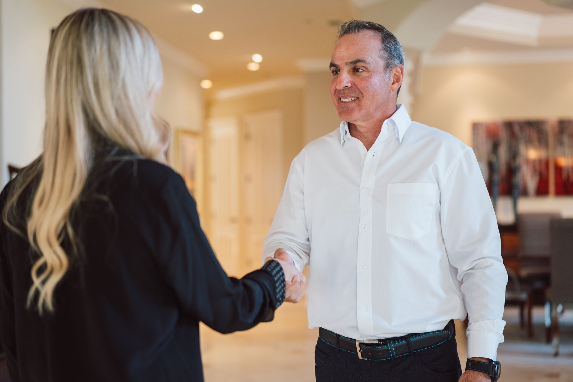 A man and a woman are shaking hands in a hallway.