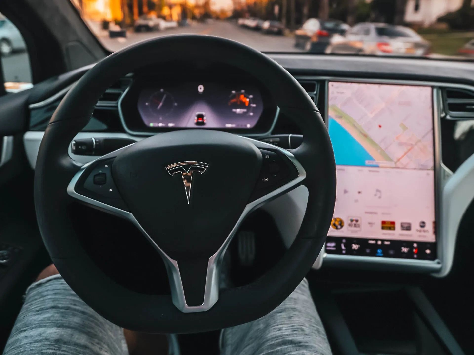 Tesla steering wheel and dashboard with center touchscreen showing navigation map inside a car