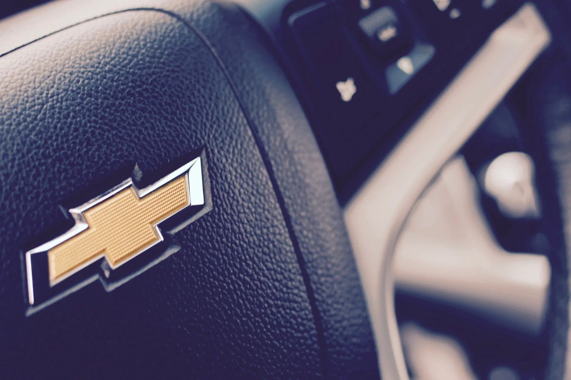 Close-up of a Chevrolet steering wheel with gold bowtie logo and visible seatbelt in a car interior