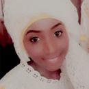 Une femme portant un foulard blanc sourit à la caméra.