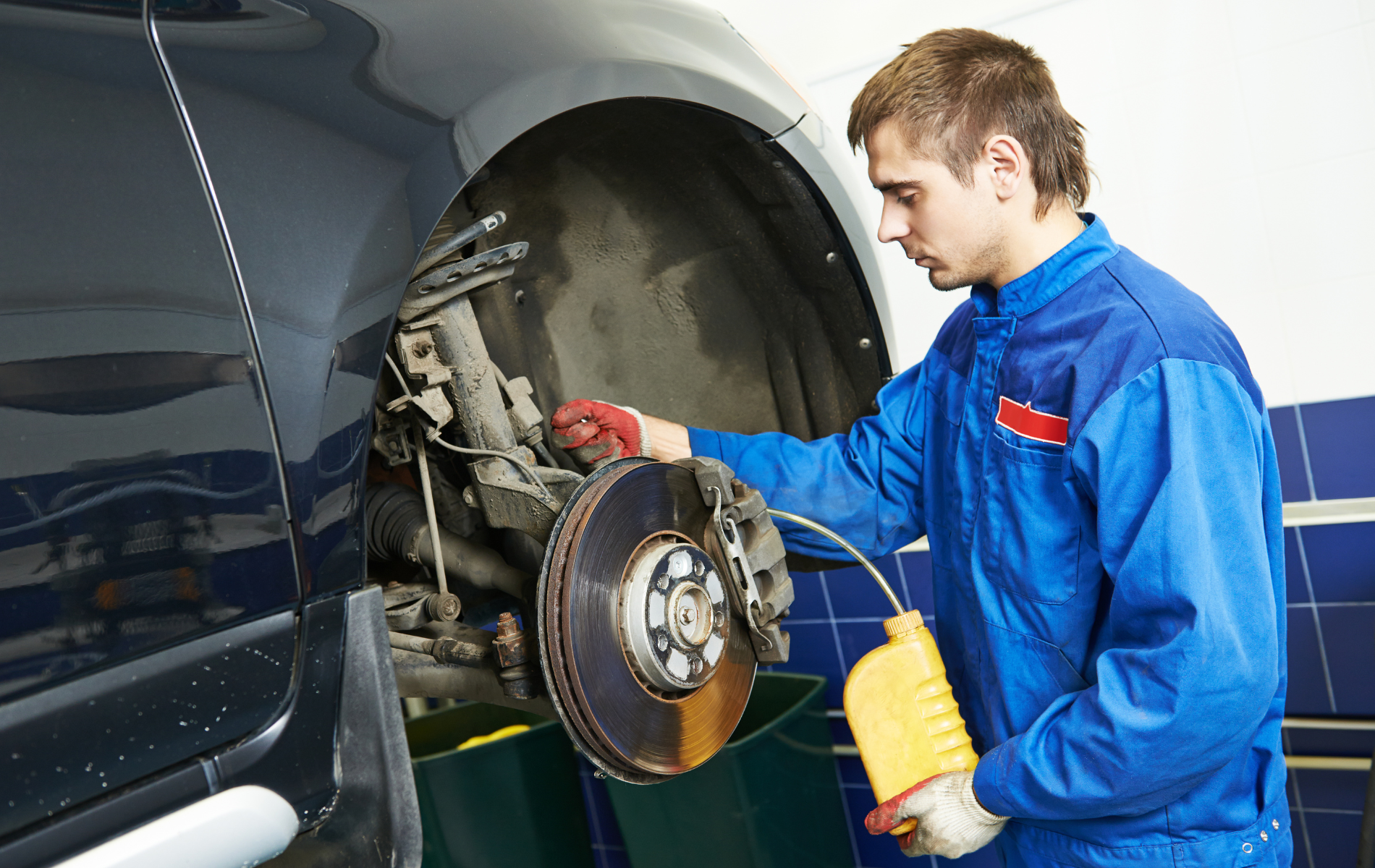 A man in a blue uniform is working on a car.