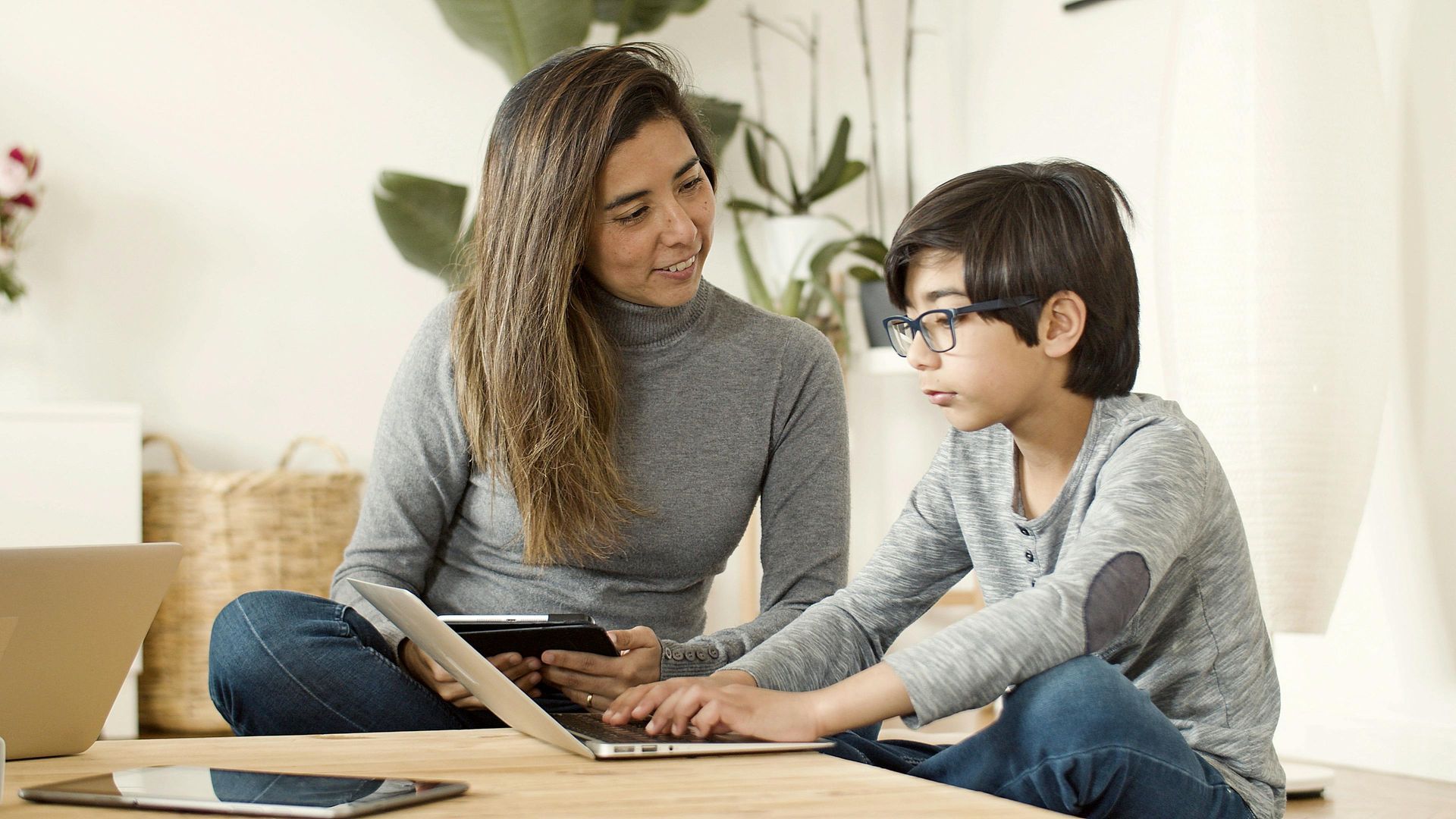 Parent helping student with online school work at home using laptop.