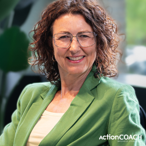 Woman with glasses and green blazer smiles. ActionCOACH logo visible.
