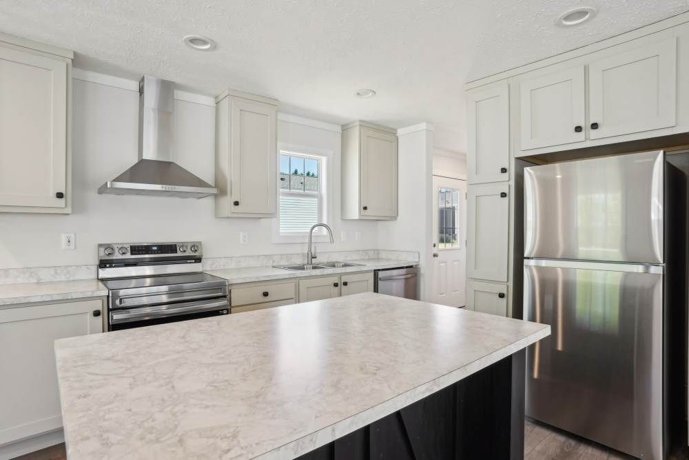 White kitchen with stainless steel appliances, light countertops, and a central island.