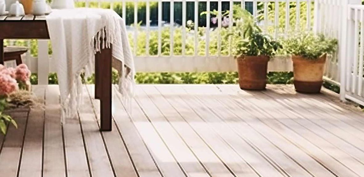 Wooden deck with potted plants and a table set for outdoor dining.