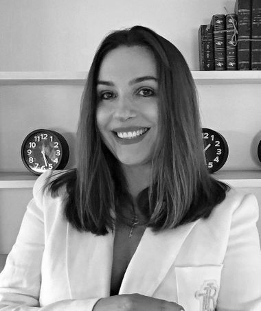 A woman in a white jacket is smiling in a black and white photo.