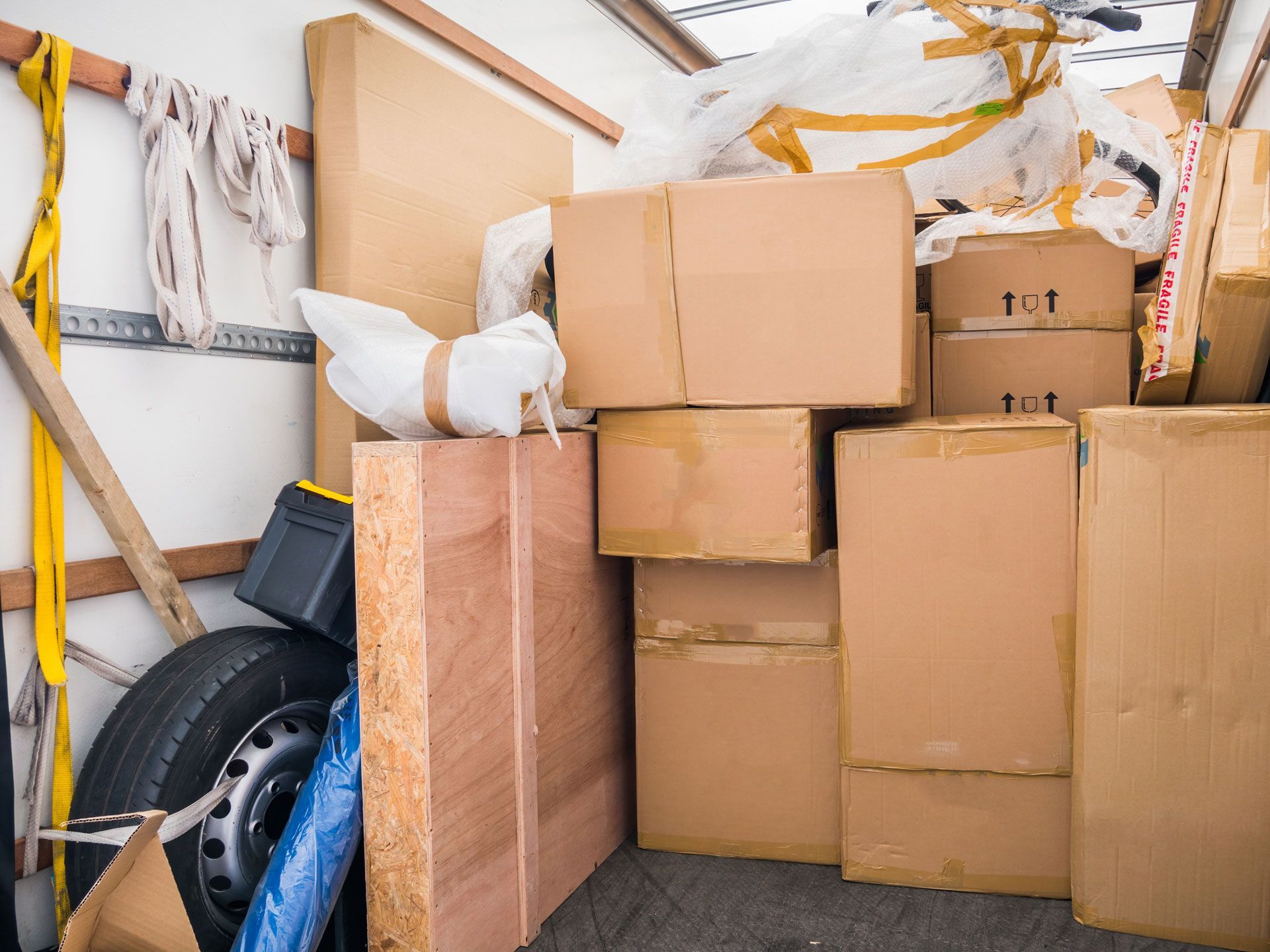 A truck filled with lots of cardboard boxes and a tire.