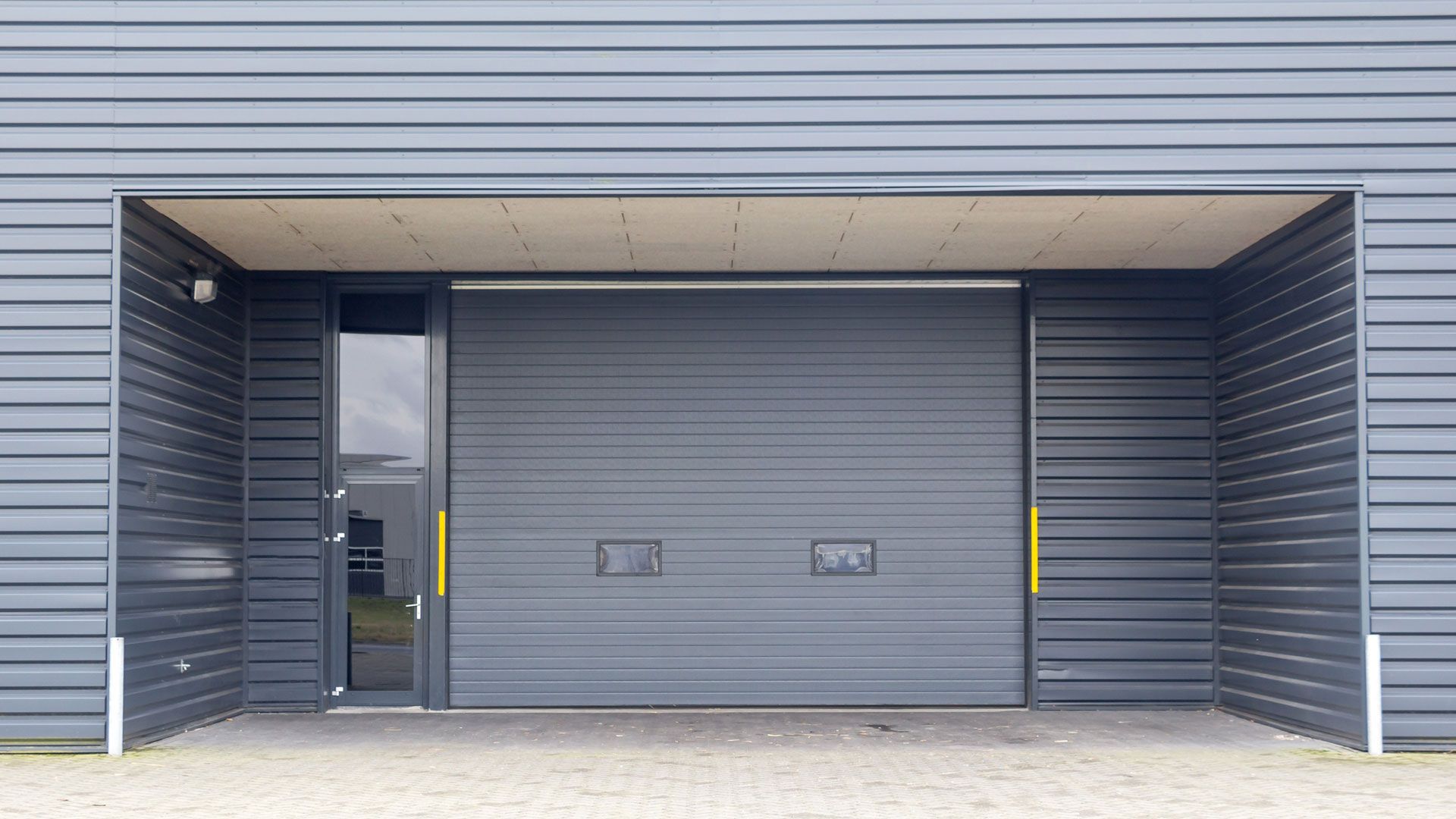 A large gray garage door is open in front of a building.