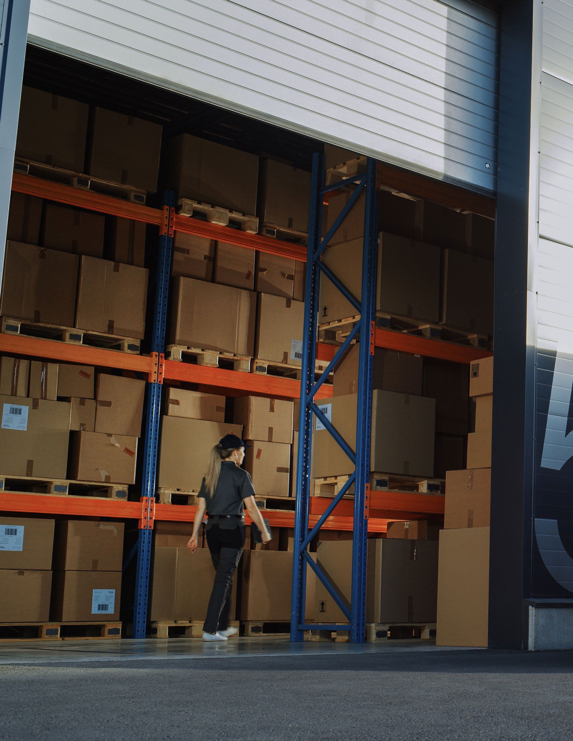 A man is standing in front of a warehouse full of boxes