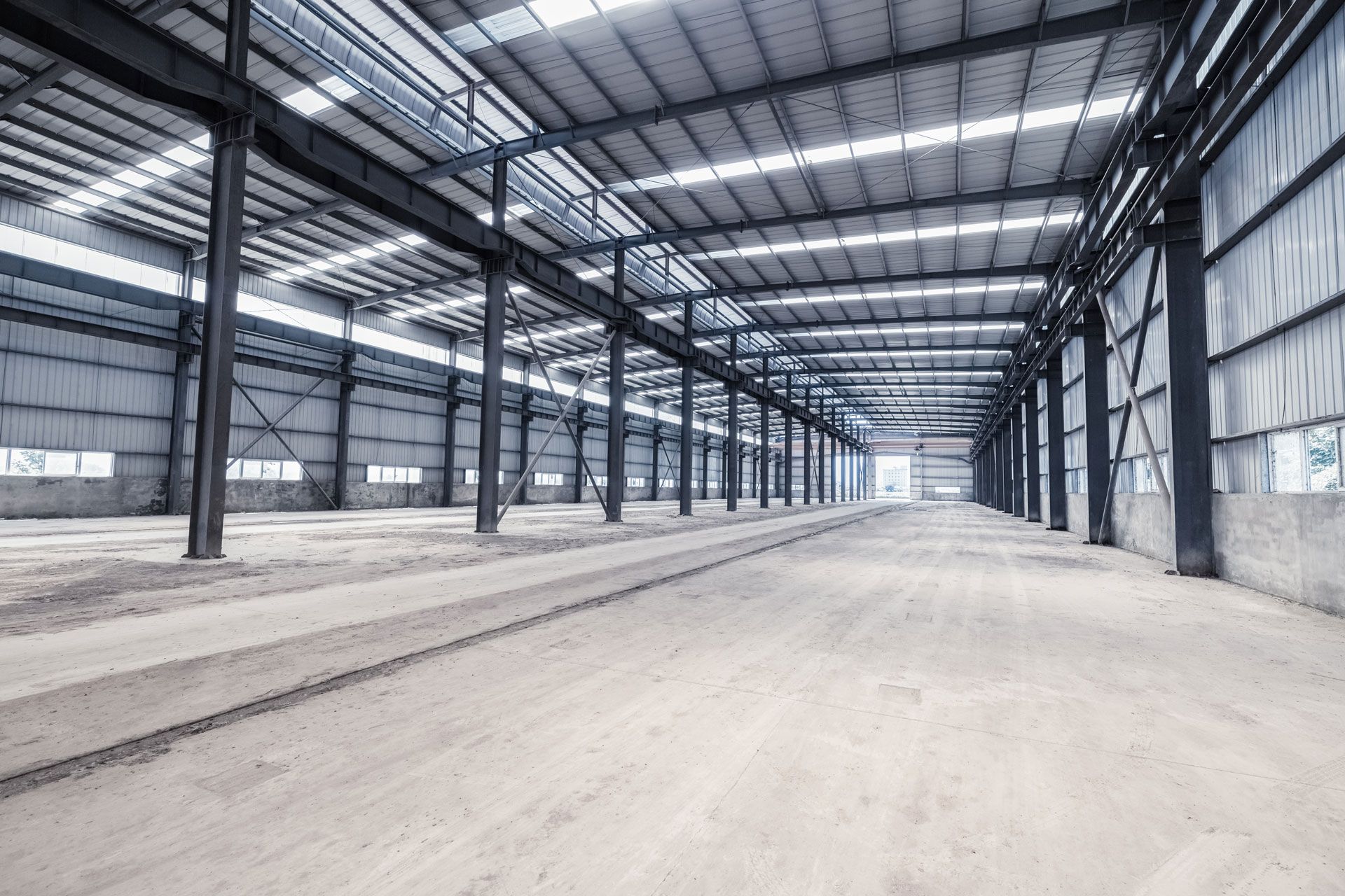 A large empty warehouse with a metal roof and a lot of windows.