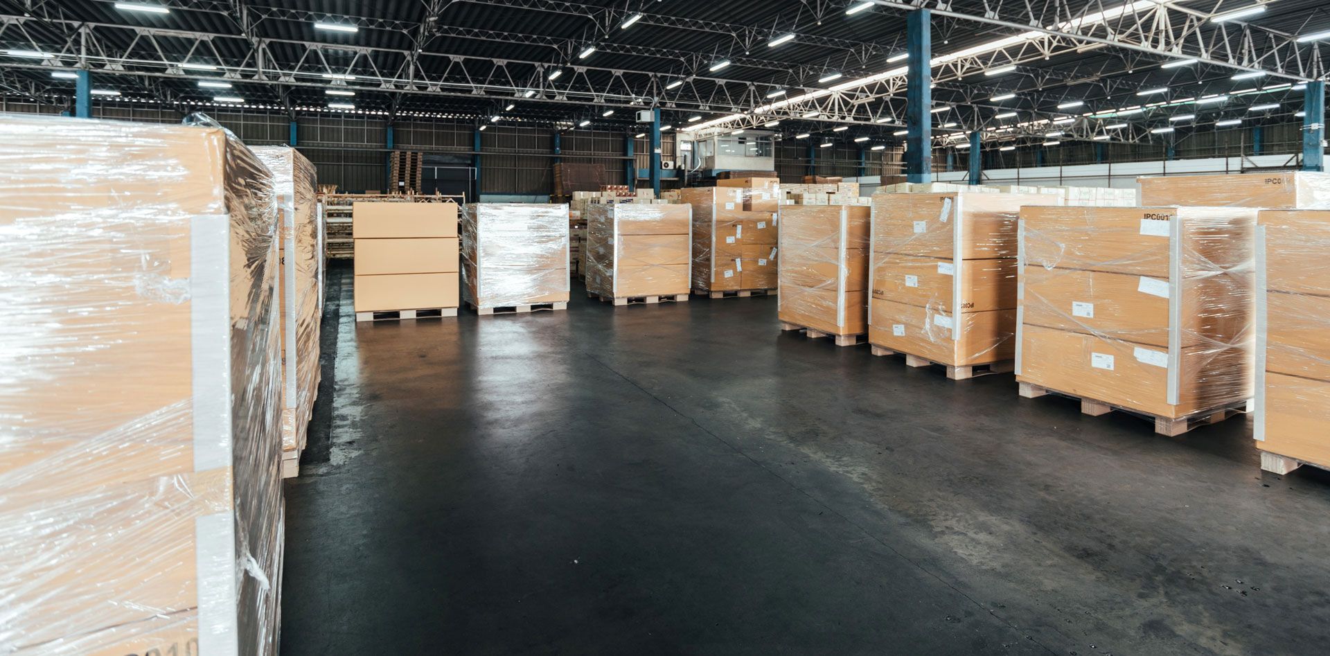 A large warehouse filled with lots of cardboard boxes wrapped in plastic.